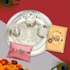 Elegantly packed Raksha Bandhan gift with silver thali, roli-chawal, greeting card, and premium Rakhi.